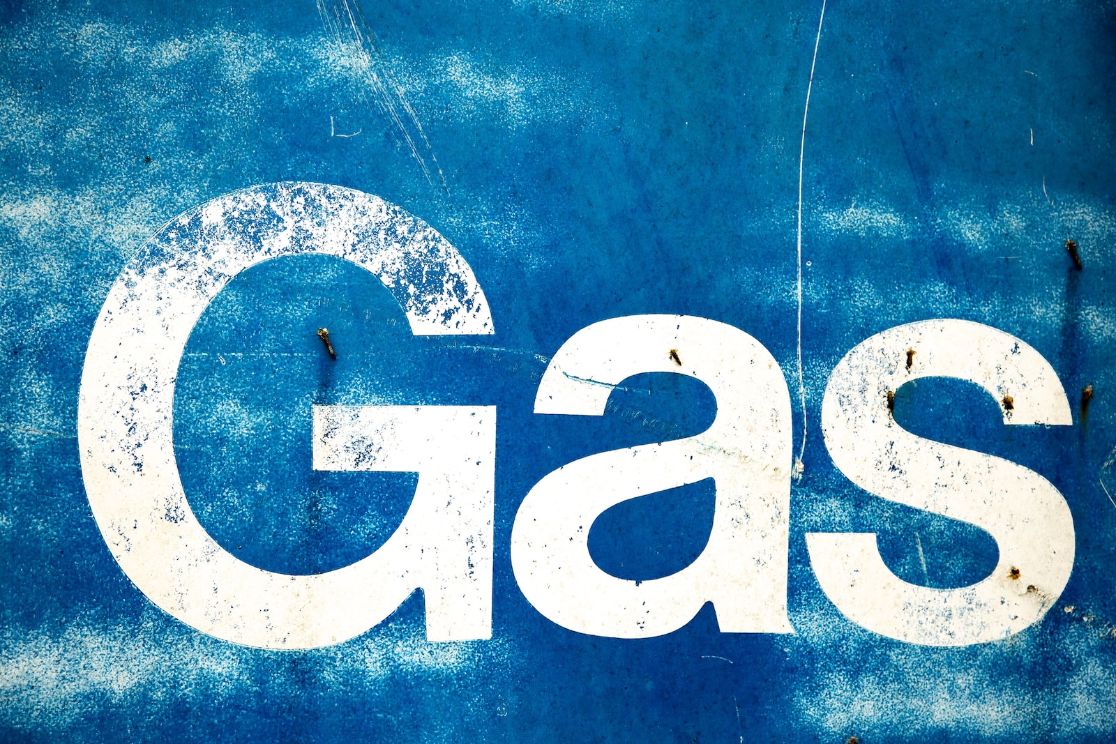 the word gas painted on the side of a blue wall